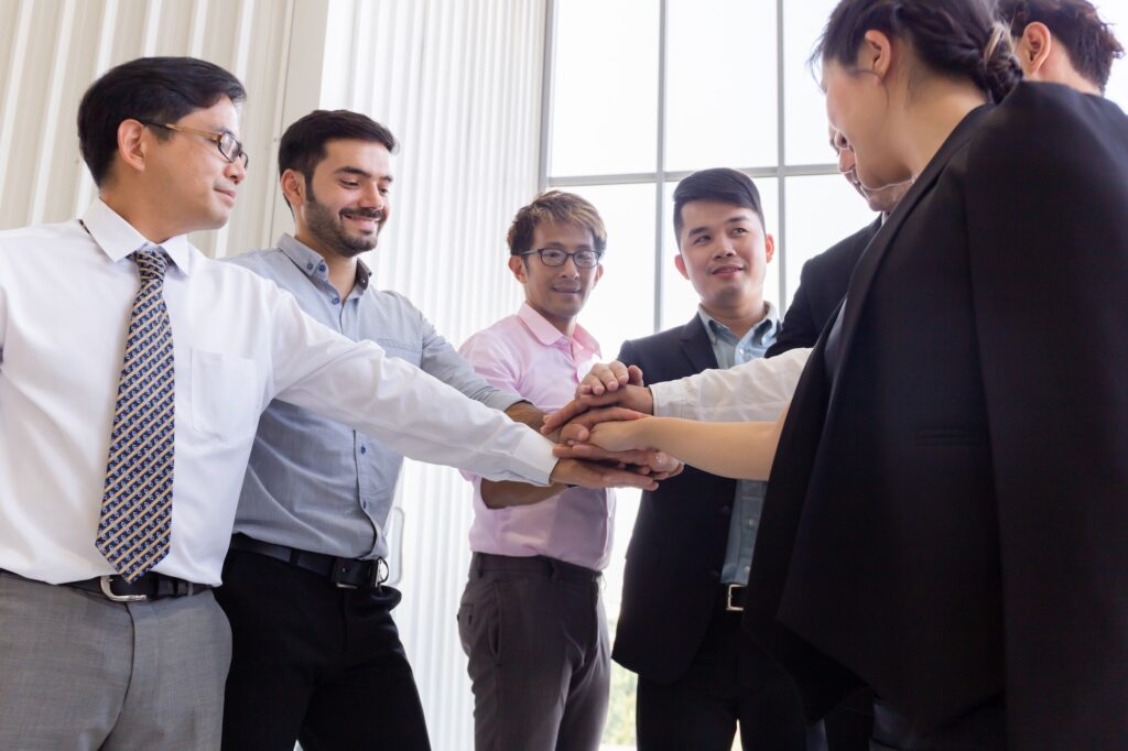Diverse colleagues stacking hands in office